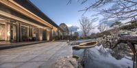 a courtyard with a pond at dusk and lights above it, which are reflected by a few stone slabs