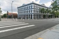 a city intersection with a building on the corner and a pedestrian crossing the street near it