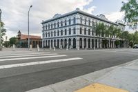 a city intersection with a building on the corner and a pedestrian crossing the street near it