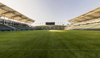 the stadium with several empty seats and grass on either side of the field there is a grass roof above the field and seating