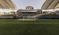 the stadium with several empty seats and grass on either side of the field there is a grass roof above the field and seating