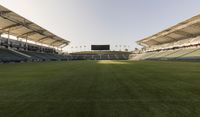 the stadium with several empty seats and grass on either side of the field there is a grass roof above the field and seating