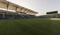 the stadium with several empty seats and grass on either side of the field there is a grass roof above the field and seating