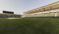 the stadium with several empty seats and grass on either side of the field there is a grass roof above the field and seating