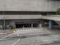 an airport has several signs in its parking garage while people walk by the walkway and stairs on the right