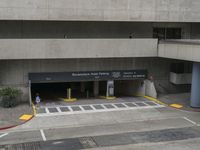 an airport has several signs in its parking garage while people walk by the walkway and stairs on the right