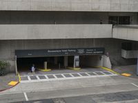 an airport has several signs in its parking garage while people walk by the walkway and stairs on the right