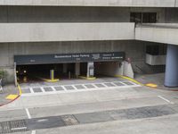 an airport has several signs in its parking garage while people walk by the walkway and stairs on the right