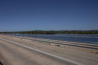 a man riding a horse on top of a bridge next to water under a blue sky