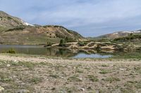 a mountain has a small lake in the foreground and some snow capped mountains behind it