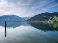 this is a lake and some mountains, with small houses, a dock and an old pier in the center