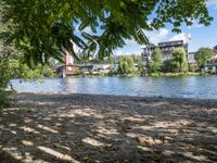 a lake in a residential area surrounded by trees and buildings, some water and people walking along the shoreline