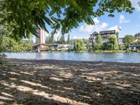 a lake in a residential area surrounded by trees and buildings, some water and people walking along the shoreline