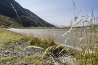 a motorcycle is on the side of a road with a mountain in the background near the grass