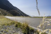 a motorcycle is on the side of a road with a mountain in the background near the grass