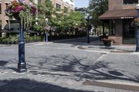 a lamp post next to a street sign near buildings and flowers in baskets along a sidewalk