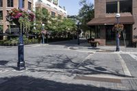 a lamp post next to a street sign near buildings and flowers in baskets along a sidewalk