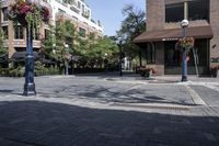 a lamp post next to a street sign near buildings and flowers in baskets along a sidewalk