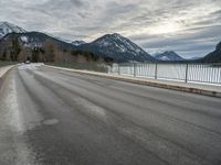 there is a man walking along the road on skateboard and wearing a jacket with a mountain backdrop