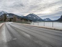 there is a man walking along the road on skateboard and wearing a jacket with a mountain backdrop