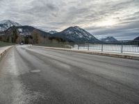 there is a man walking along the road on skateboard and wearing a jacket with a mountain backdrop