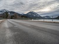 there is a man walking along the road on skateboard and wearing a jacket with a mountain backdrop