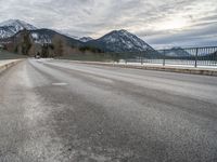 there is a man walking along the road on skateboard and wearing a jacket with a mountain backdrop