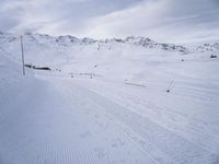 snow covered slope in the middle of a ski area as people ski on it near ski lift