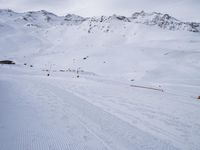 snow covered slope in the middle of a ski area as people ski on it near ski lift