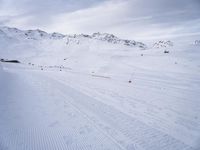 snow covered slope in the middle of a ski area as people ski on it near ski lift