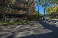 a couple of tall buildings next to trees on a street corner that is empty of pedestrians