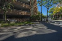 a couple of tall buildings next to trees on a street corner that is empty of pedestrians
