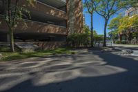 a couple of tall buildings next to trees on a street corner that is empty of pedestrians