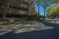 a couple of tall buildings next to trees on a street corner that is empty of pedestrians