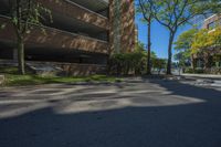 a couple of tall buildings next to trees on a street corner that is empty of pedestrians