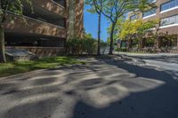 a couple of tall buildings next to trees on a street corner that is empty of pedestrians