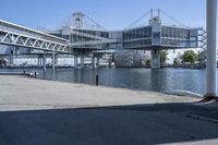 a man walking across a bridge over a river next to some buildings and cars under a bridge