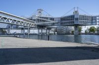 a man walking across a bridge over a river next to some buildings and cars under a bridge