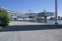 a man walking across a bridge over a river next to some buildings and cars under a bridge