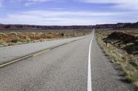 the long straight road stretches out into the distance to the horizon in the desert, with a lone motorcycle on the side