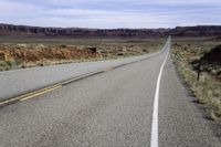 the long straight road stretches out into the distance to the horizon in the desert, with a lone motorcycle on the side