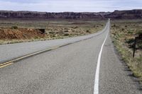 the long straight road stretches out into the distance to the horizon in the desert, with a lone motorcycle on the side