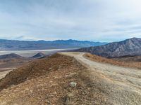 dirt road and mountain, with barren landscape in the background from the summit of mountaintop