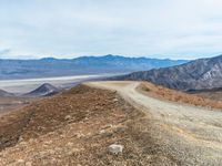 dirt road and mountain, with barren landscape in the background from the summit of mountaintop