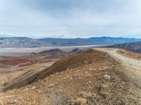 dirt road and mountain, with barren landscape in the background from the summit of mountaintop