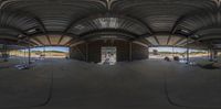 a wide angle view of the inside of a large barn with a bicycle ramp and workers working on it