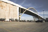 large bridge over parking lot in industrial area next to building with light post on top