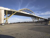 large bridge over parking lot in industrial area next to building with light post on top