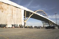 large bridge over parking lot in industrial area next to building with light post on top