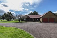 a large house sitting in the middle of a field with a grassy area and trees